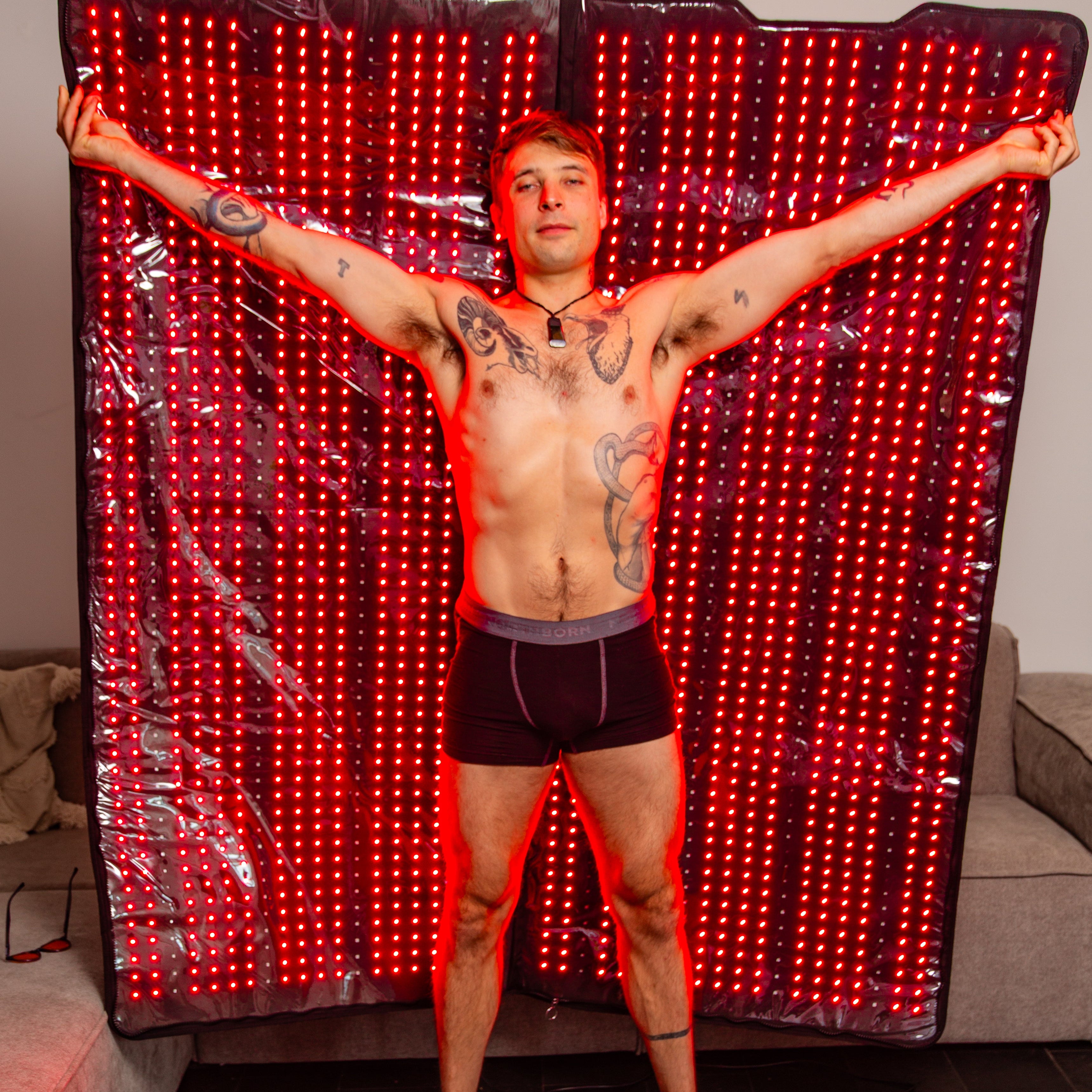 Man with tattoos standing in front of a red LED curtain