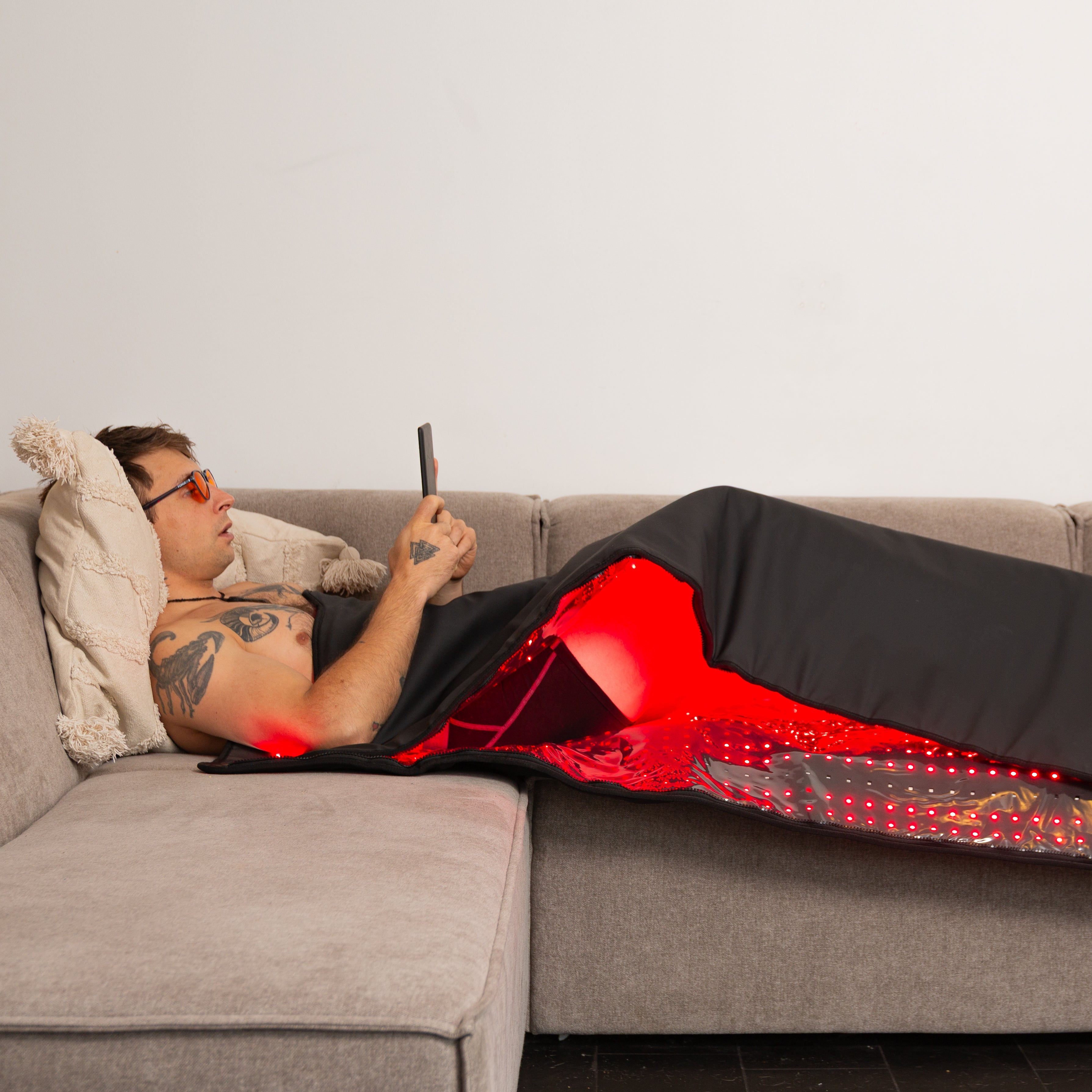 Person lying on a couch with a red and black LED blanket
