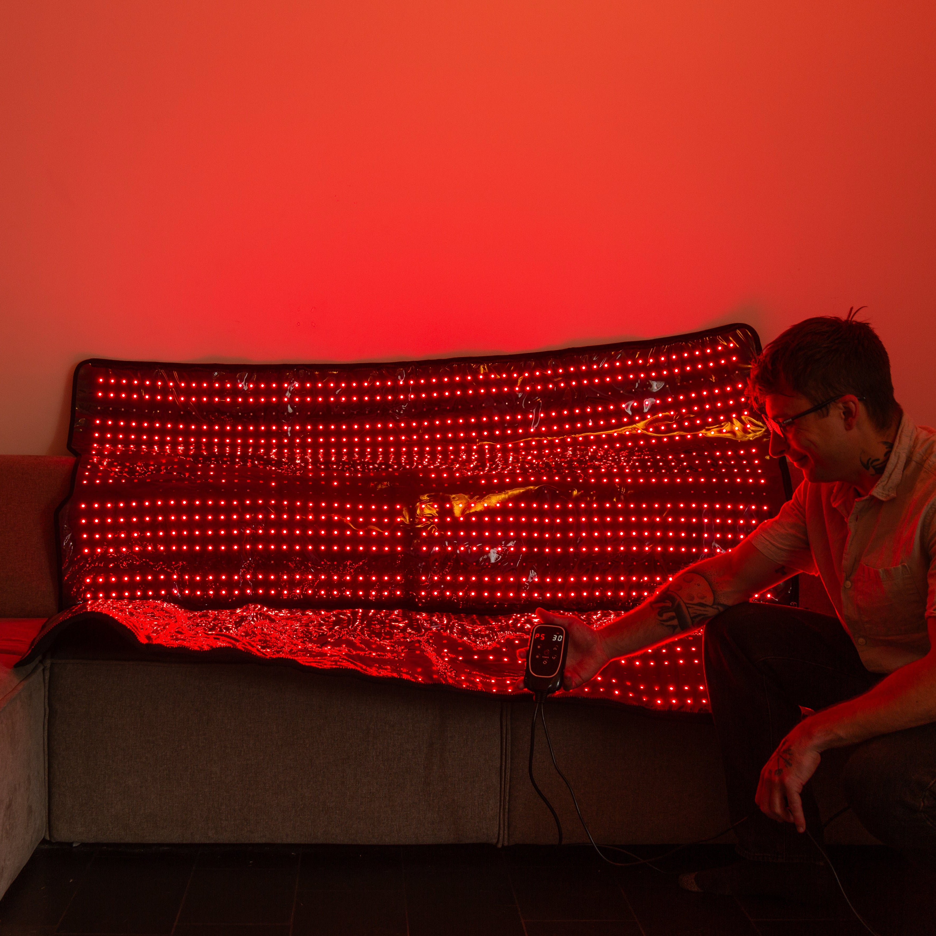 Person interacting with a LED blanket in a room with red lighting